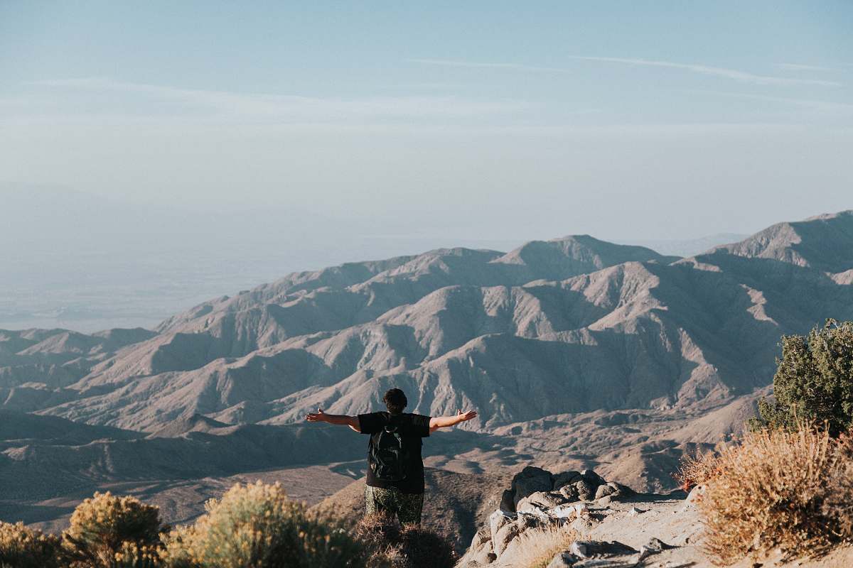 grey person standing on top of mountain mountain